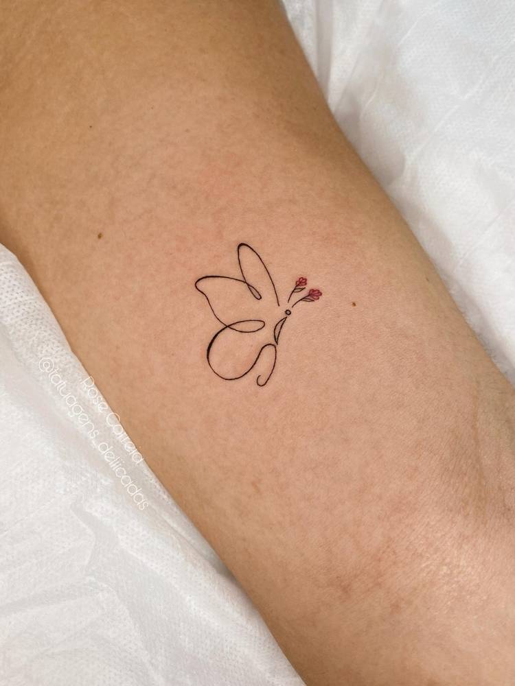 minimalista-flor-borboleta Ttuagem de borboleta em traço fino minimalista, cujas antenas são em formato de rosas. Ela foi feita no interior do braço de uma mulher de pele clara.