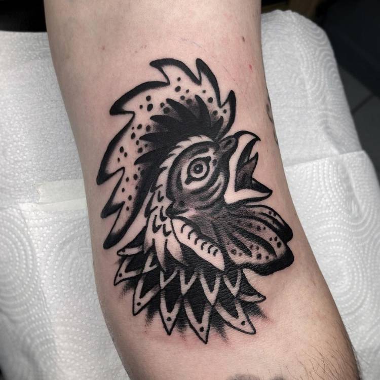 Pessoa de pele clara tatuada com galo old school preto