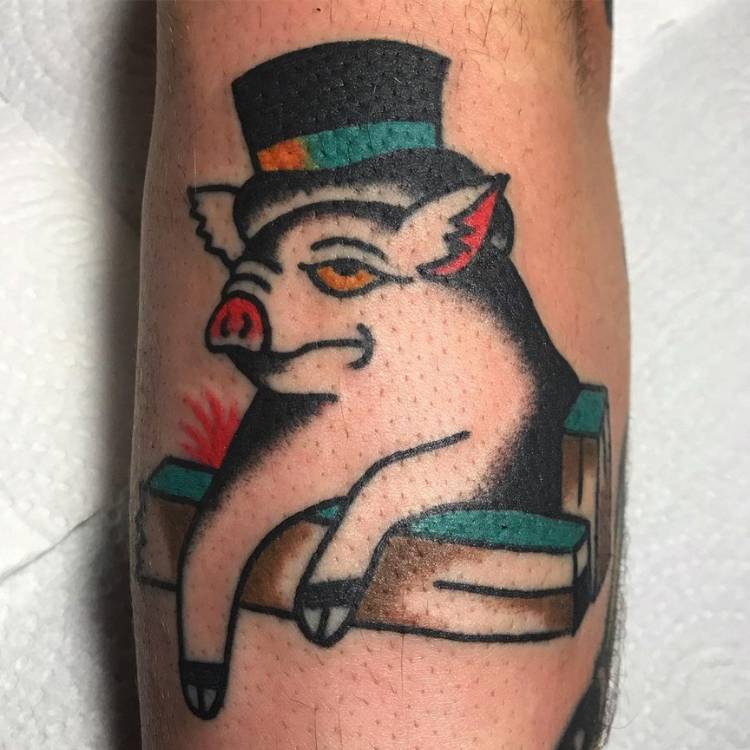 Pessoa de pele clara tatuada com porco old school de cartola, em preto e azul