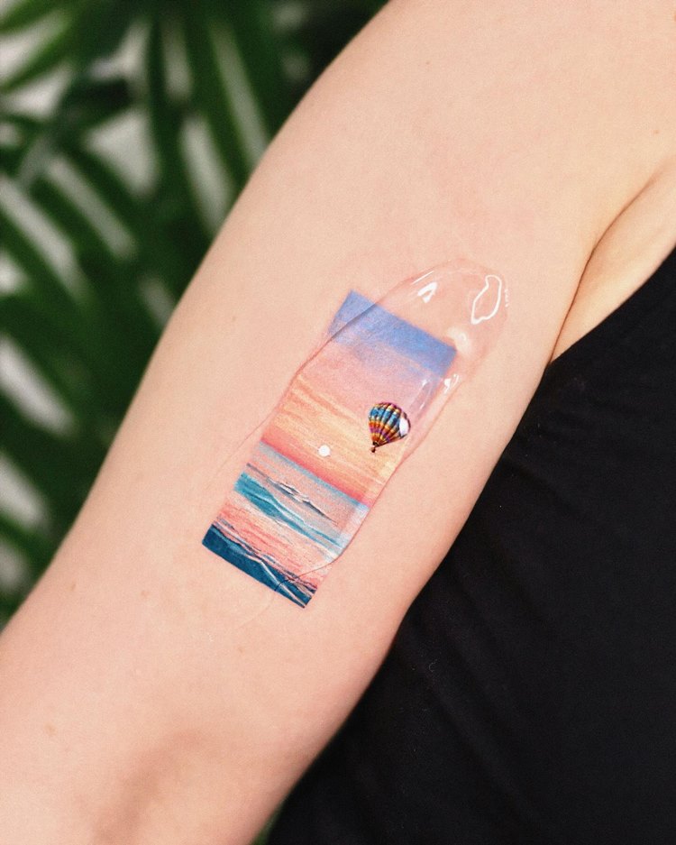 Tatuagem pintura balão de ar quente  voando no mar no pôr do sol com álcool em gel em cima
