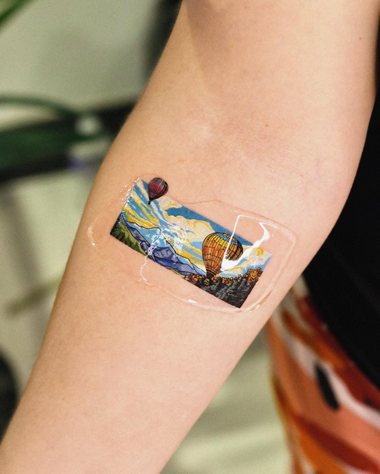 tatuagem de pintura de balão de ar quente sobrevoando em meio a algumas montanhas