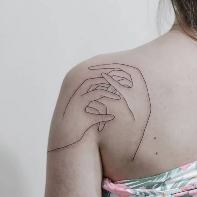 tatuagem-feminina-ombro-atras-mao Mulher de pele clara de costas com tatuagem fine line de duas mãos