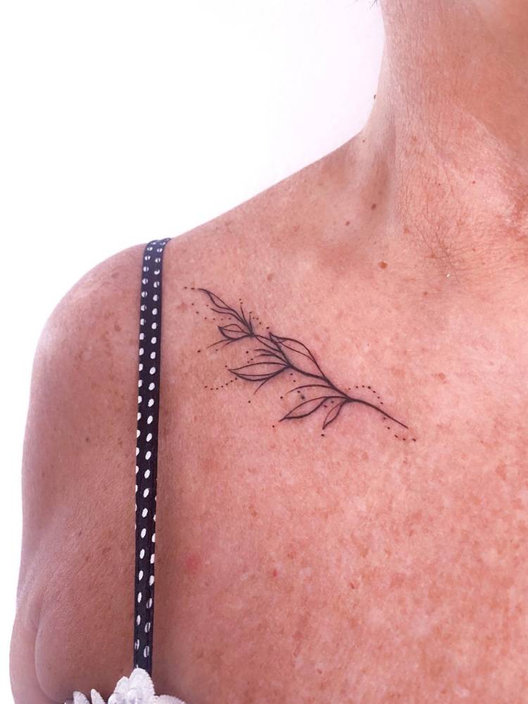 tatuagem-feminina-ombro-delicada-ramo Mulher de pele clara com muitas sardas e tatuagem delicada de ramos no ombro