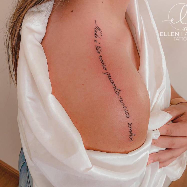 tatuagem-feminina-ombro-frase-pescoco Mulher de pele clara com tatuagem de frase no ombro do pescoço até o começo do braço, com a frase "Nada é tão nosso quanto nossos sonhos"