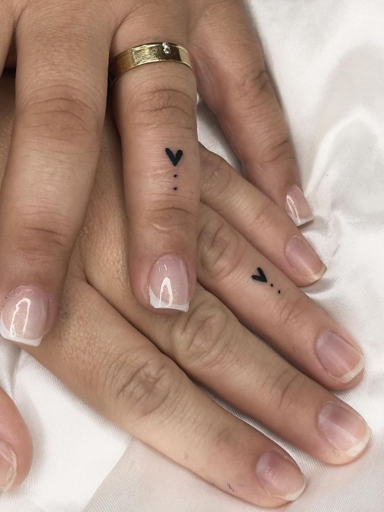 Anelares tatuados com pequenos corações e pontinhos