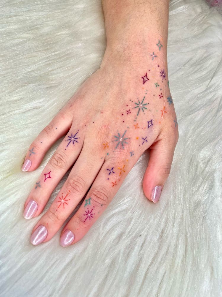 Mão tatuada com constelação colorida