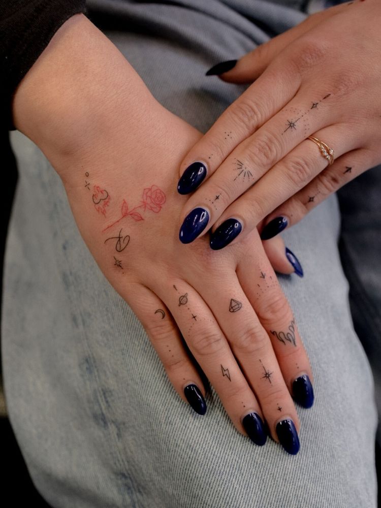 Mãos de pele clara com pequenos desenhos em fineline em preto e vermelho