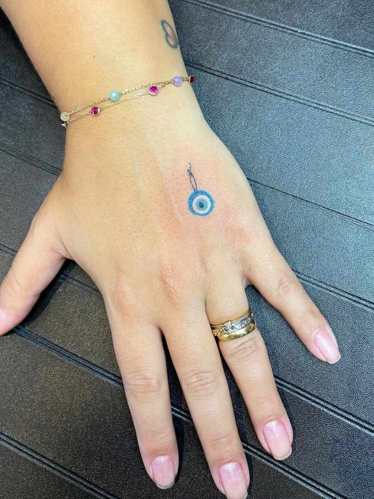Mão feminina com pequeno olho grego colorido