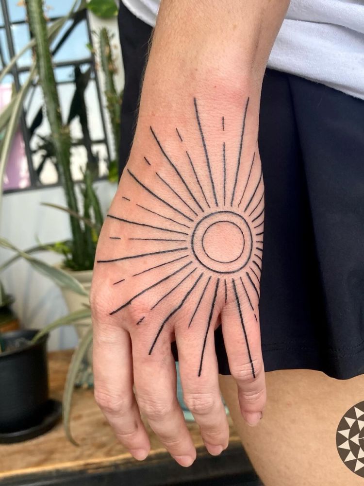 Foto de mão com sol fineline no dorso