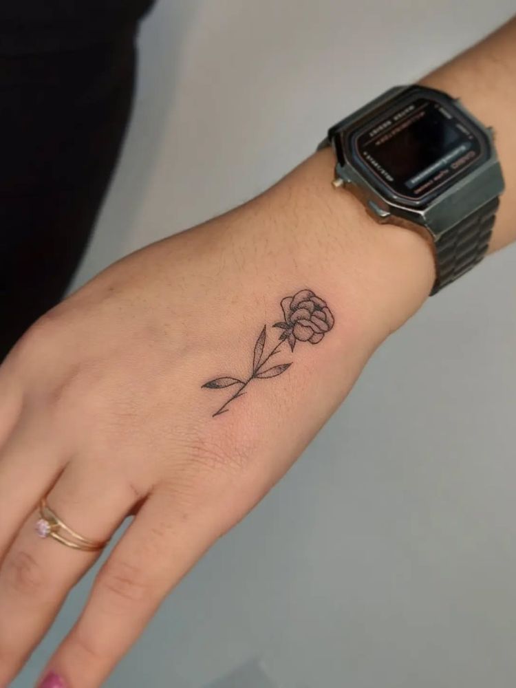 Mão com rosa fineline e pulso com relógio