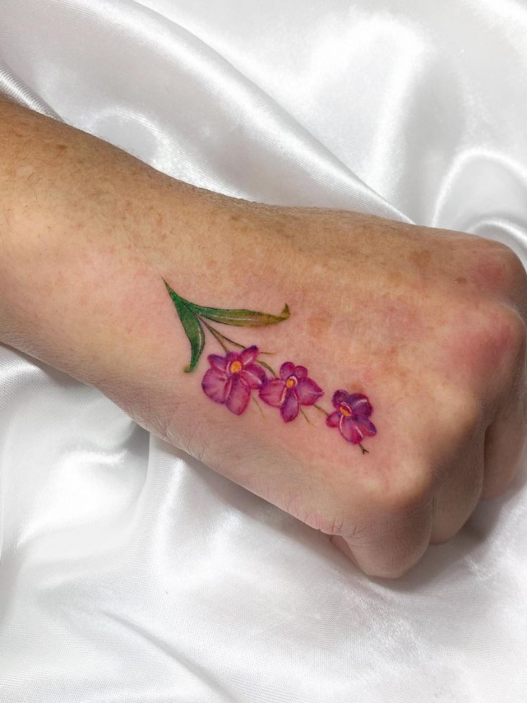 Mão fechada com ramo de orquídeas em rosa