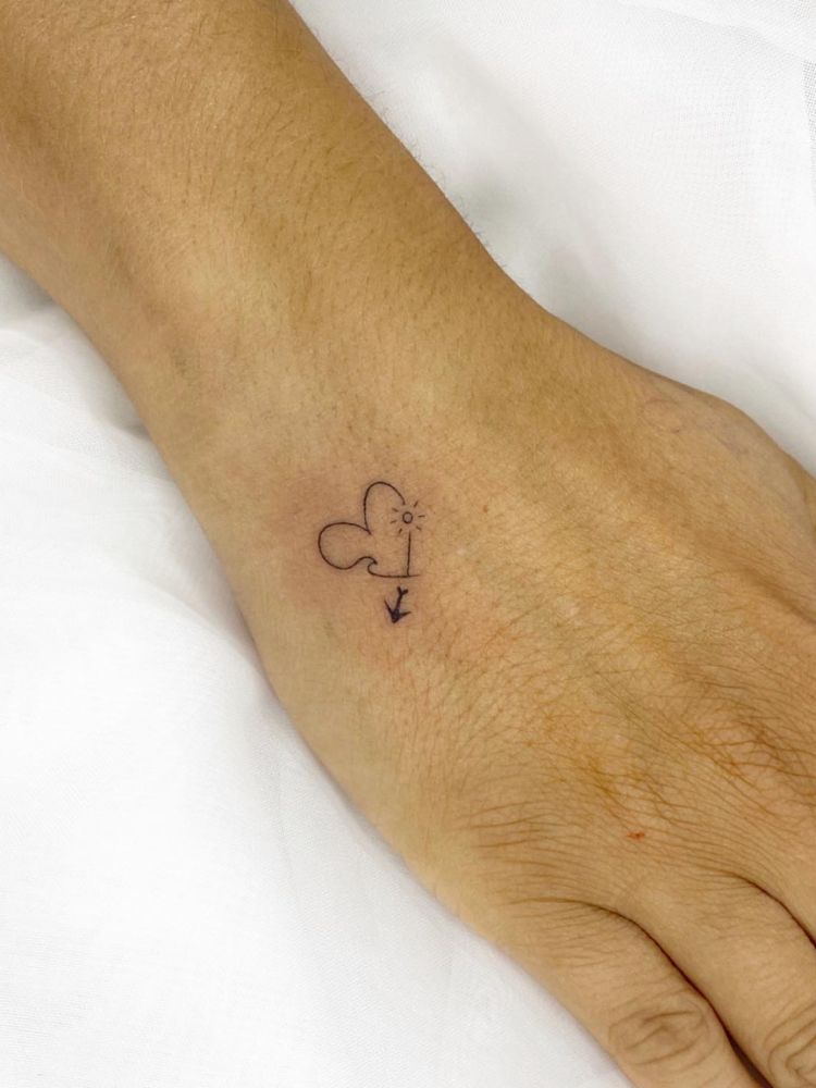 Mão com tatuagem fineline de coração, onda, sol e avião