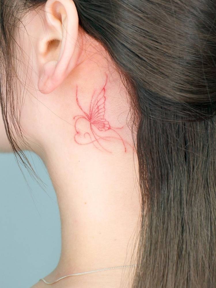 traco-vermelho-nuca-colorida Tatuagem de borboleta em traço fino vermelho na nuca de uma mulher de pele clara e cabelo liso marrom.